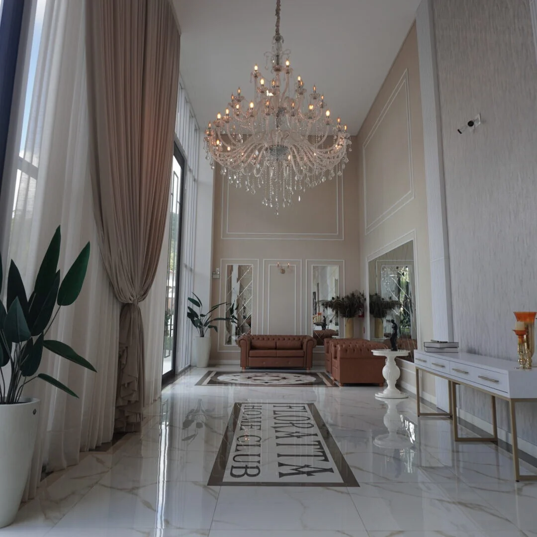 Hall do Floratta Home Club com acabamento em tons claros e lustre central
